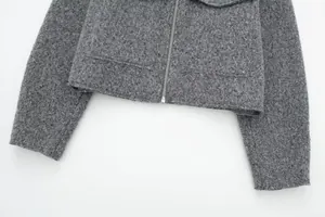 Detailansicht der grauen Bouclé-Textur an der kurzen Jacke mit silbernem Reißverschluss