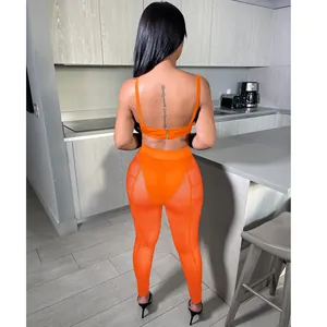 Back view of vibrant orange two-piece set with mesh leggings and crop top on model