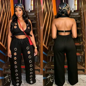 Black two-piece set featuring halter crop top and wide-leg trousers with metal grommets