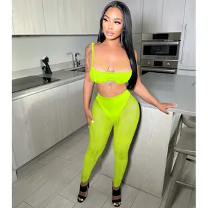 Full body view of a neon green mesh two-piece set with strappy top and sheer leggings.