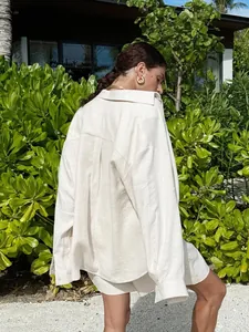 Back view detail of a loose cream cotton shirt and shorts set in a tropical outdoor setting