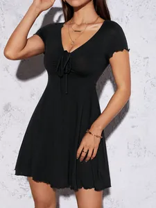 Gros plan d'une robe noire à col en V avec nœud papillon et manches à volants