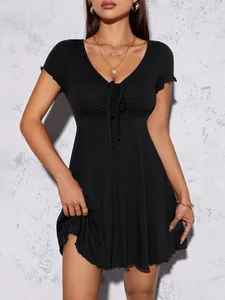 Gros plan d'une robe courte noire avec col en V et nœud décoratif sur le devant.