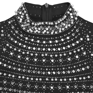 Detalle de un elegante vestido negro con adornos de pedrería y perlas en el cuello alto.