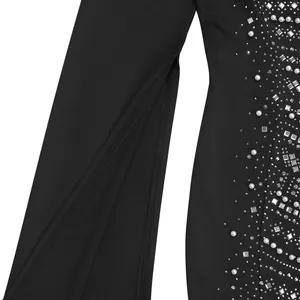 Primer plano de un vestido negro elegante con mangas abiertas, diamantes y perlas