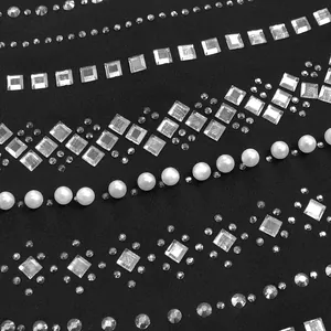 Detalle macro de un elegante vestido de noche con pedrería termofijada y perlas blancas