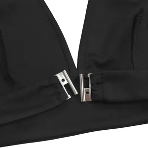 Close-up high-quality detail of a silver metal front clasp on a black fashion top garment