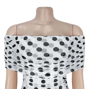 Nahaufnahme der schwarzen Polka-Dot-Netzstruktur und Raffung am weißen Partykleid.