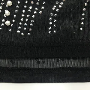 Detail of black mesh fabric with sparkling rhinestones and elegant pearls for sexy evening dress.