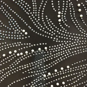 Close-up of shimmering rhinestone and pearl patterns on black mesh dress fabric