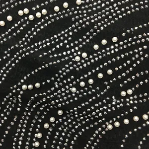 Close-up of black mesh see-through fabric with wavy rhinestone and pearl embellishments