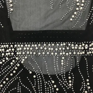 Detailed view of black mesh dress featuring elegant white pearls and sparkling rhinestone patterns