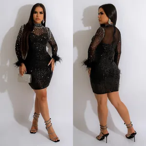Detailed view of black sequined mini dress with rhinestone mesh top and feather cuffs