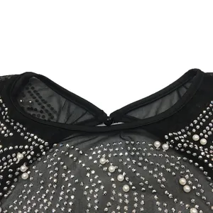 Detailed macro view of black mesh dress featuring shimmering rhinestones and faux pearls