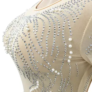Close-up view of nude mesh dress featuring intricate rhinestone and pearl detailing