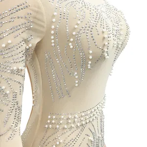 Close-up detail of sparkling rhinestones and pearls on a sheer nude mesh party dress