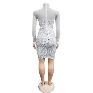 Back view of white long sleeve mini dress with silver sequins and feather cuffs.