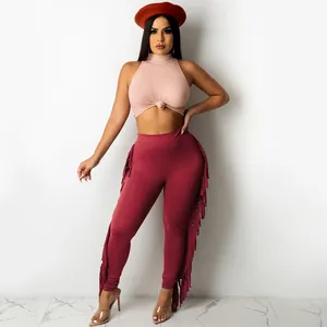 Full body view of the pink ribbed sleeveless top and burgundy leggings with long fringe