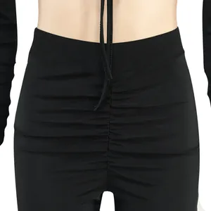 Détail en gros plan d'un pantalon noir froncé à taille haute avec un design à lacets