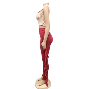 Side view of pink sleeveless crop top and red skinny pants with fringe details.