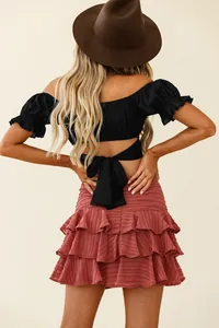 Back view of black off-the-shoulder tie-back top with ruffled sleeves and tiered skirt