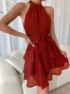 Detail shot of a stylish rust red halter neck tiered dress with ruffles and waist tie