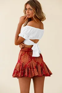 Back view of a white off-the-shoulder ruffle crop top with a stylish back-tie knot detail.