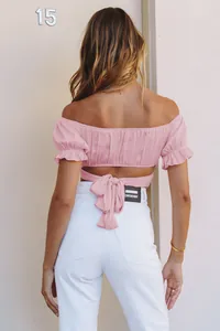Back view of a pink off-the-shoulder crop top with a feminine tie-back and ruffle sleeves.