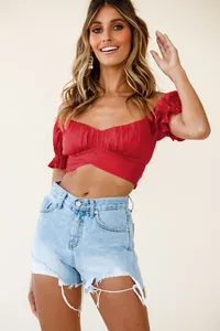 Close-up detail of sexy red off-shoulder crop top with ruffles and criss-cross waist