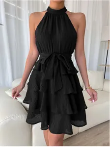 Close-up of black sleeveless halter dress with tiered ruffle layers and bow belt