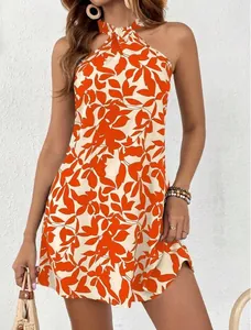 Close-up of sleeveless halter neck dress featuring vibrant orange floral leaf print.