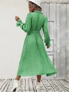 Back view of a vibrant green floral pleated long sleeve dress showing the waist belt detail