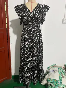 Dettaglio di un abito lungo nero con scollo a V, pois bianchi e volant