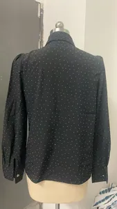 Back view of black long-sleeved shirt with rhinestone polka dots on mannequin