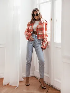 Full view of the stylish orange plaid wool jacket styled with light jeans and glasses