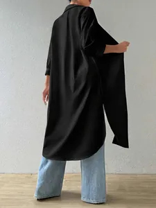 Back view of a long-line black fashion shirt showing the elegant drape and curved hem