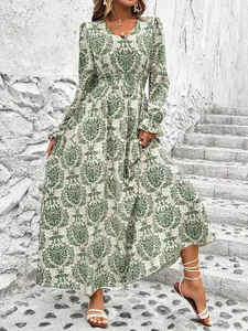 Detail view of green damask print maxi dress with V-neck and long sleeves on stairs.