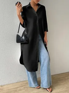 Full view of a long black button-down shirt cardigan styled with jeans and a handbag.