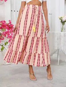 Detailed view of bohemian tiered maxi skirt with pink stripes and decorative yellow tassels.