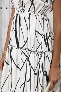 Close-up detail of abstract print and ruffled hem on a white V-neck maxi dress