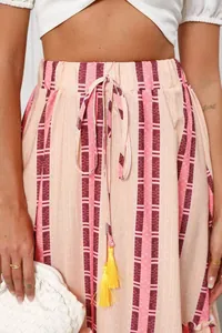 Close-up of bohemian printed maxi skirt with drawstring waist and yellow tassels.
