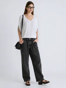 Professional shot of a white V-neck knit top paired with black wide-leg jeans and bag