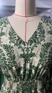 Detail view of a V-neck maxi dress featuring a vibrant green floral pattern on mannequin