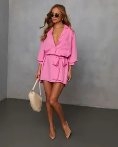 Detailed shot of a pink long-sleeved belted shirt dress with chic styling accessories