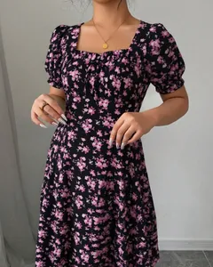 Close-up detail of elegant black floral dress with pink blossoms and square neck