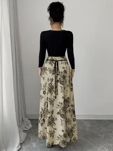 Back view of an elegant floral print maxi dress with black long sleeves and tie belt.