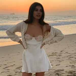 Sexy witte satijnen slipdress met kant en vest op het strand bij zonsondergang uitzicht