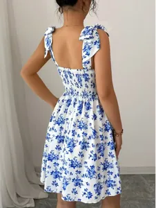 Back view of floral tie-strap dress showing smocked detail and blue flower print