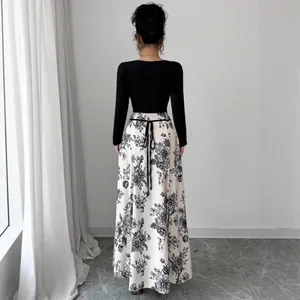 Elegant black long-sleeve dress with floral print skirt and waist tie back