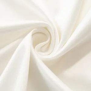 Macro detail van gladde witte satijnen stof met zachte textuur en elegante glans.